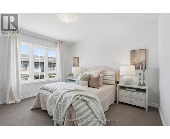 A bedroom with a large bed and a window with curtains.