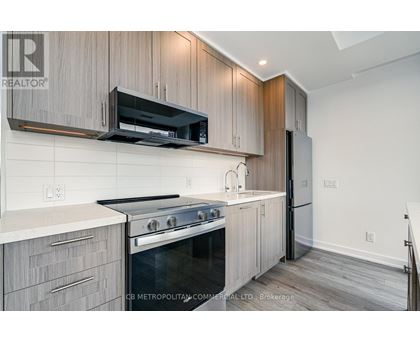 A modern kitchen with wooden cabinets and a stainless steel refrigerator.
