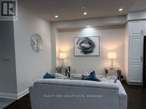 A living room with a grey couch and a painting on the wall.