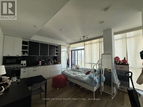 A bedroom with a bed, chair, and a table with a lamp on it.