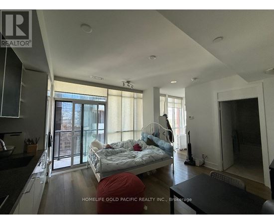 A bedroom with a bed, a couch, and a vacuum cleaner.