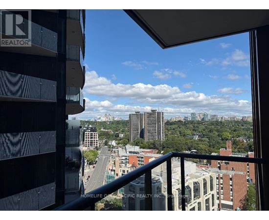 A view from a window of a cityscape with buildings and a cloudy sky.