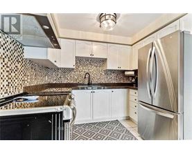 A kitchen with a black and white tiled backsplash and a stainless steel refrigerator.