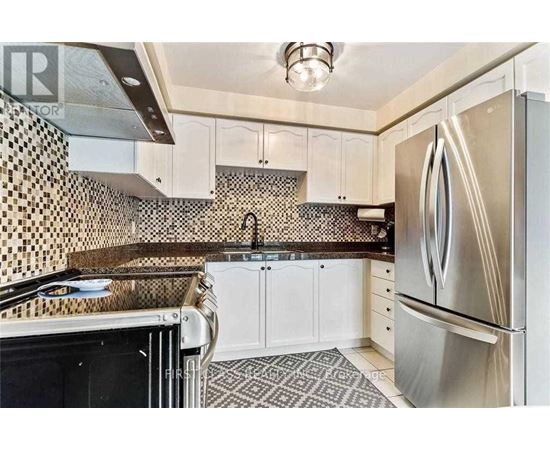 A kitchen with a black and white tiled backsplash and a stainless steel refrigerator.