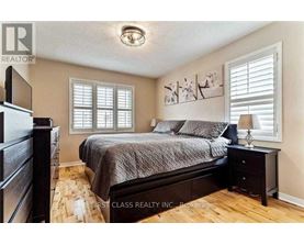 A bedroom with a bed, nightstand, and a painting on the wall.