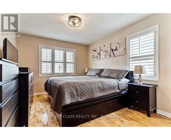 A bedroom with a bed, nightstand, and a painting on the wall.