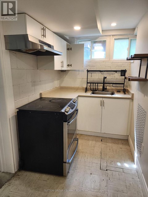 A kitchen with a black fridge and white cabinets is for sale.