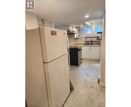 A white refrigerator in a kitchen with a counter and cabinets.