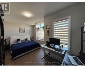 A bedroom with a bed, desk, and window with blinds.