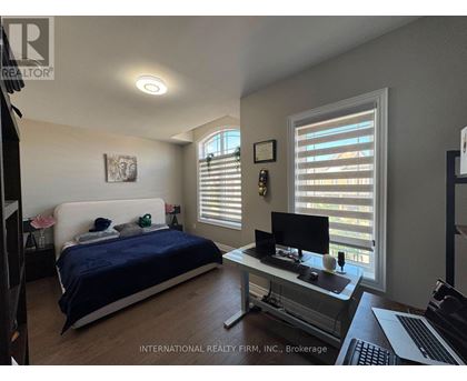 A bedroom with a bed, desk, and window with blinds.