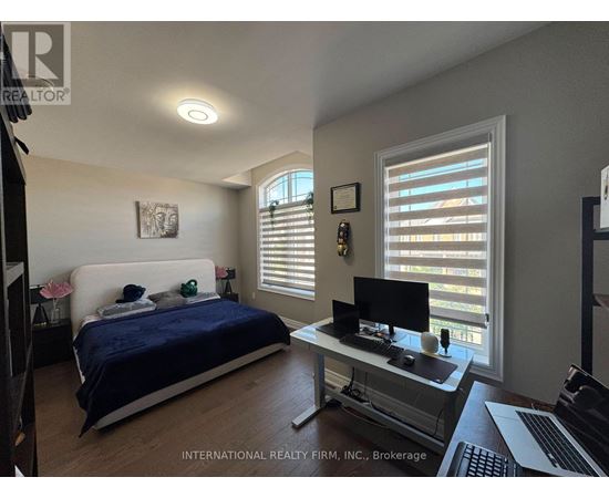 A bedroom with a bed, desk, and window with blinds.