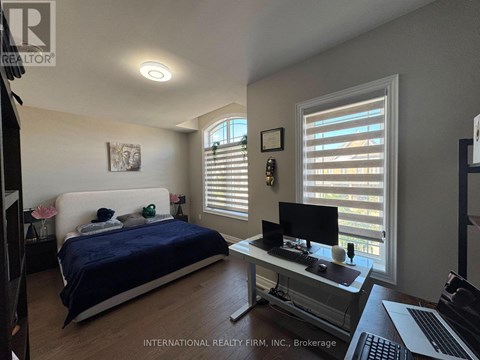A bedroom with a bed, desk, and window with blinds.