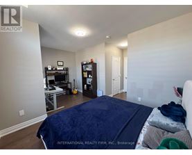 A bedroom with a bed, a desk with a computer, a bookshelf, and a guitar.