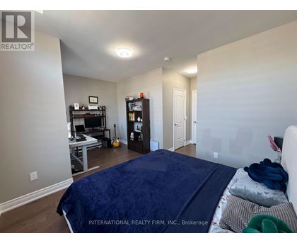 A bedroom with a bed, a desk with a computer, a bookshelf, and a guitar.