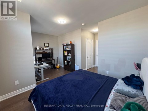 A bedroom with a bed, a desk with a computer, a bookshelf, and a guitar.