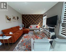 A living room with a brown sofa, a white armchair, and a patterned rug.