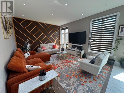 A living room with a grey rug and a brown sofa.