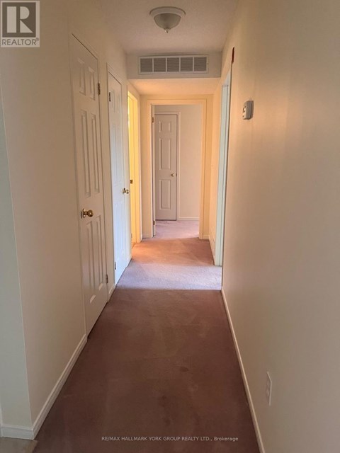 A long hallway with white walls and a brown floor.