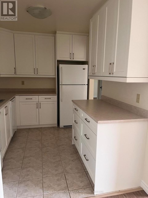 A kitchen with white cabinets and a white refrigerator.