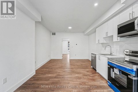 A kitchen with white cabinets and a wooden floor.