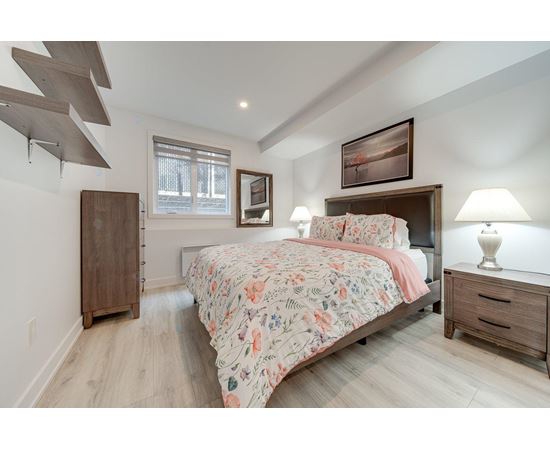 A bedroom with a large bed and a wooden dresser.