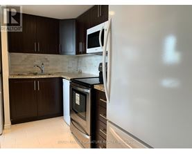 A kitchen with a white fridge, black oven, and brown cabinets.