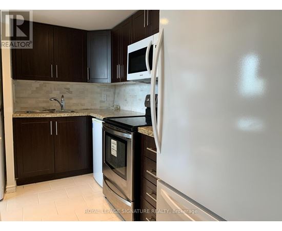 A kitchen with a white fridge, black oven, and brown cabinets.
