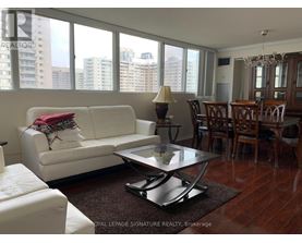A white couch with a red pillow is in the middle of a room with a glass table and chairs.