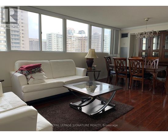A white couch with a red pillow is in the middle of a room with a glass table and chairs.