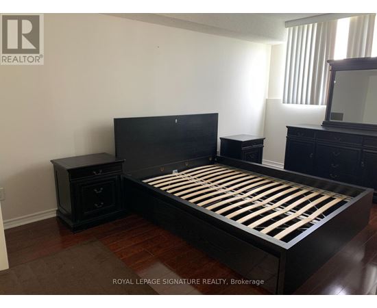 A bedroom with a black bed and wooden floors.