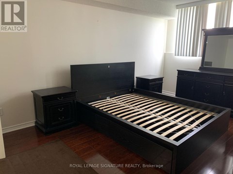 A bedroom with a black bed and wooden floors.