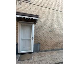 A white door is on the left side of a brick wall.