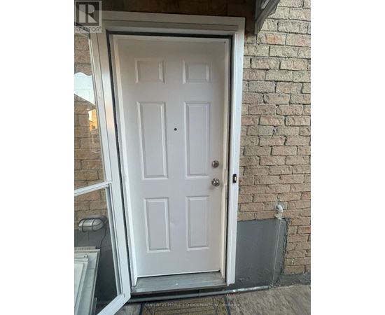 A white door with a black handle is set in a brick wall.