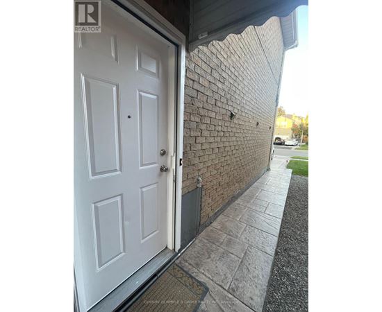 A white door is open to a brick wall.