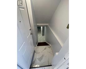 A hallway with a white door and a marble floor.