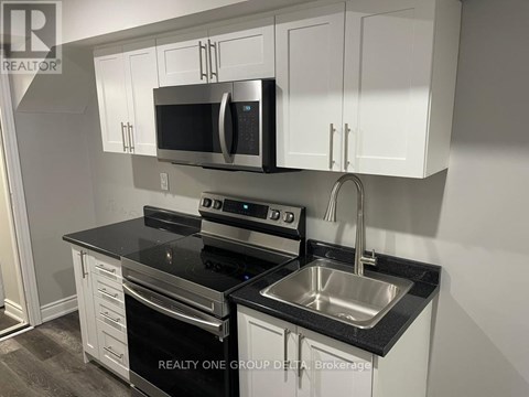 A kitchen with white cabinets and black countertops.