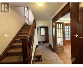A hallway with a staircase and a door on the right.