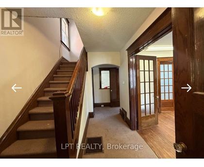 A hallway with a staircase and a door on the right.