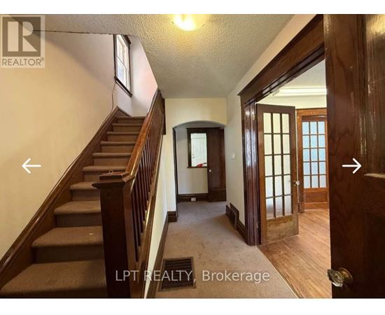 A hallway with a staircase and a door on the right.