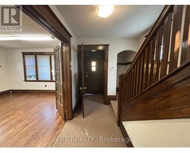 A hallway with wood floors and a staircase.