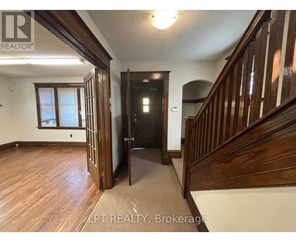 A hallway with wood floors and a staircase.