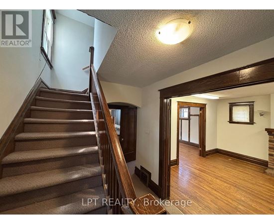 A staircase with a wooden banister and steps leading up to a doorway.