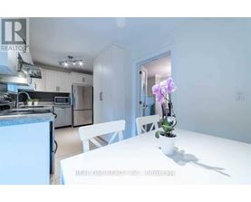 A white dining table with a vase of flowers on it in a kitchen.