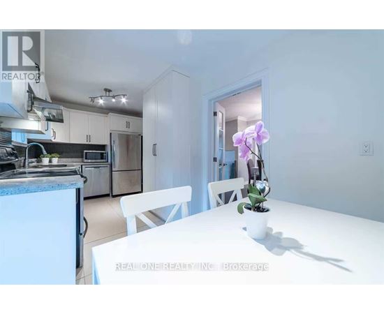 A white dining table with a vase of flowers on it in a kitchen.