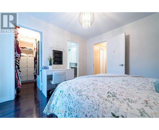 A bedroom with a large bed and a desk with a chair.