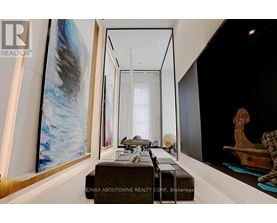 A modern living room with a large painting on the wall and a long table with chairs.