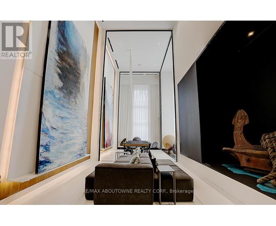 A modern living room with a large painting on the wall and a long table with chairs.