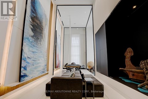 A modern living room with a large painting on the wall and a long table with chairs.