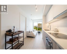 A modern kitchen with white cabinets and a wooden shelf.