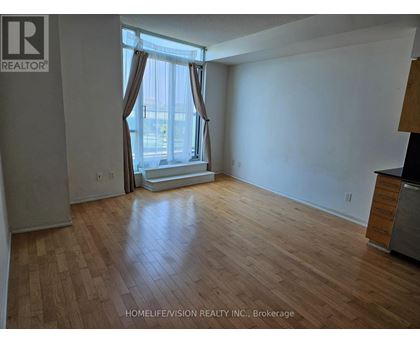 A room with wooden flooring and a window with curtains.